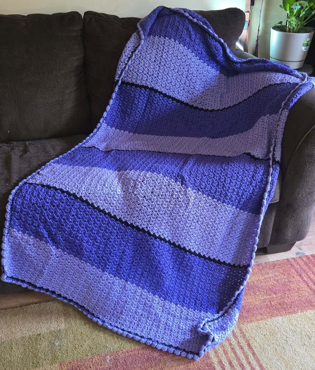 Purple Passion handmade crocheted afghan displayed on a sofa